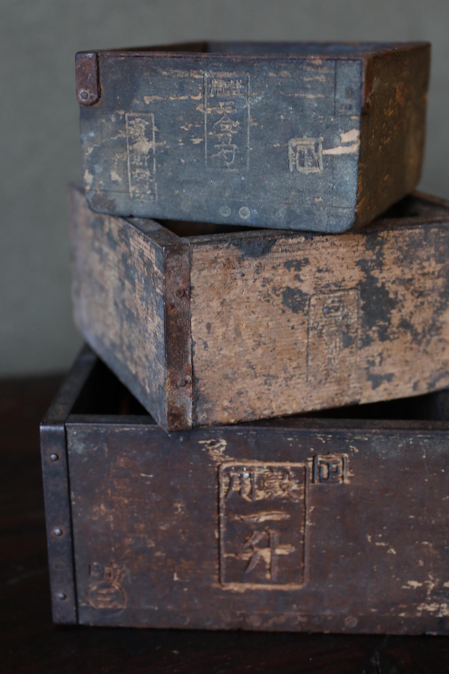 A stack of three old, weathered wooden crates or boxes, with visible signs of age and wear.