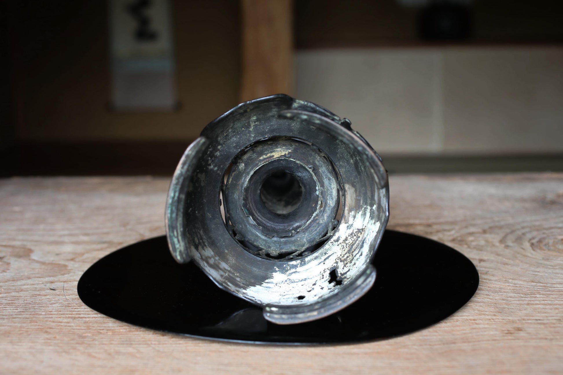 a metal object with a circular opening, sitting on a black circular surface.