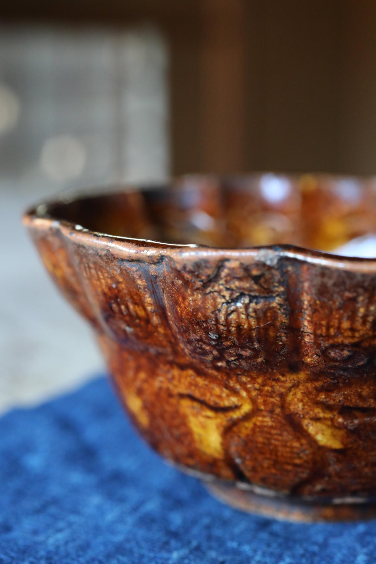 A close-up image of a brown, textured ceramic bowl resting on a blue surface.