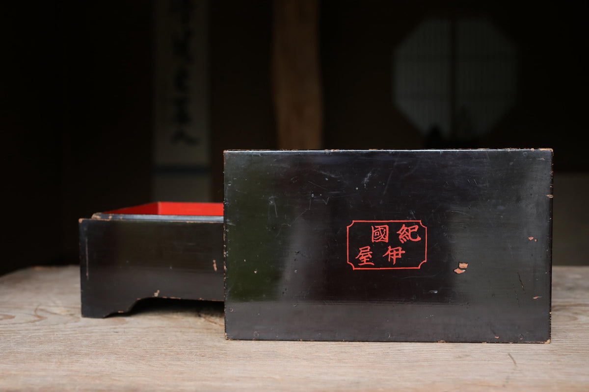 A black wooden box with a red interior, featuring a red Chinese character on its surface.