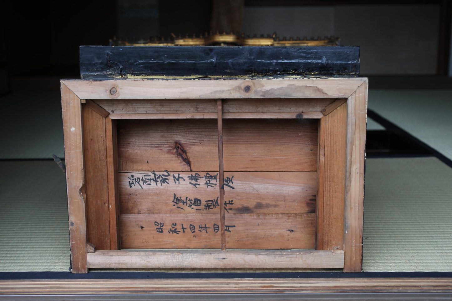 a wooden box with Japanese text on it, placed on a tatami mat.
