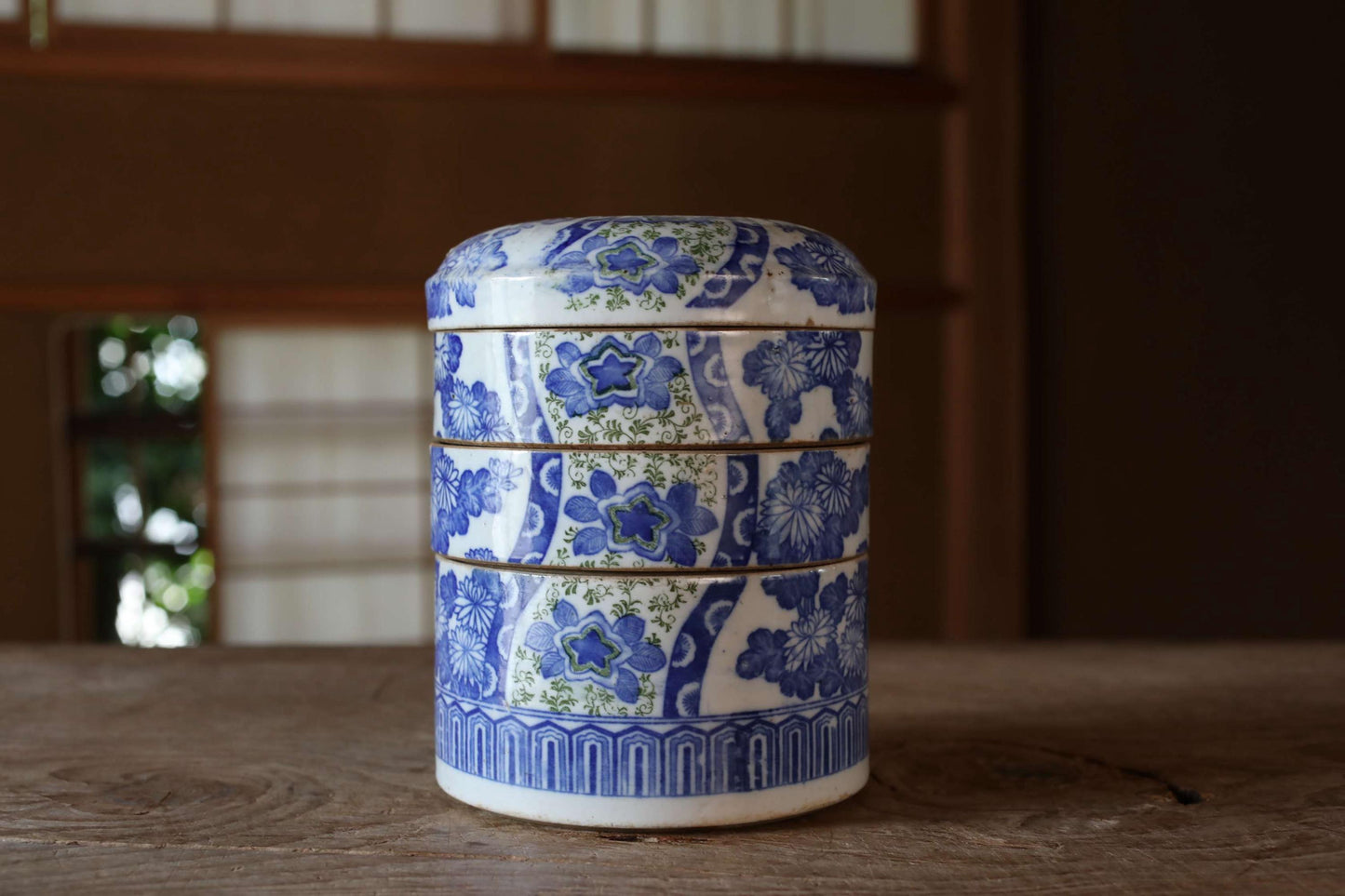 A decorative blue and white ceramic container with a floral pattern sits on a wooden surface.