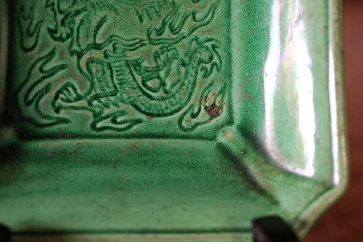 A close-up view of a green ceramic dragon sculpture, with intricate details and patterns visible.