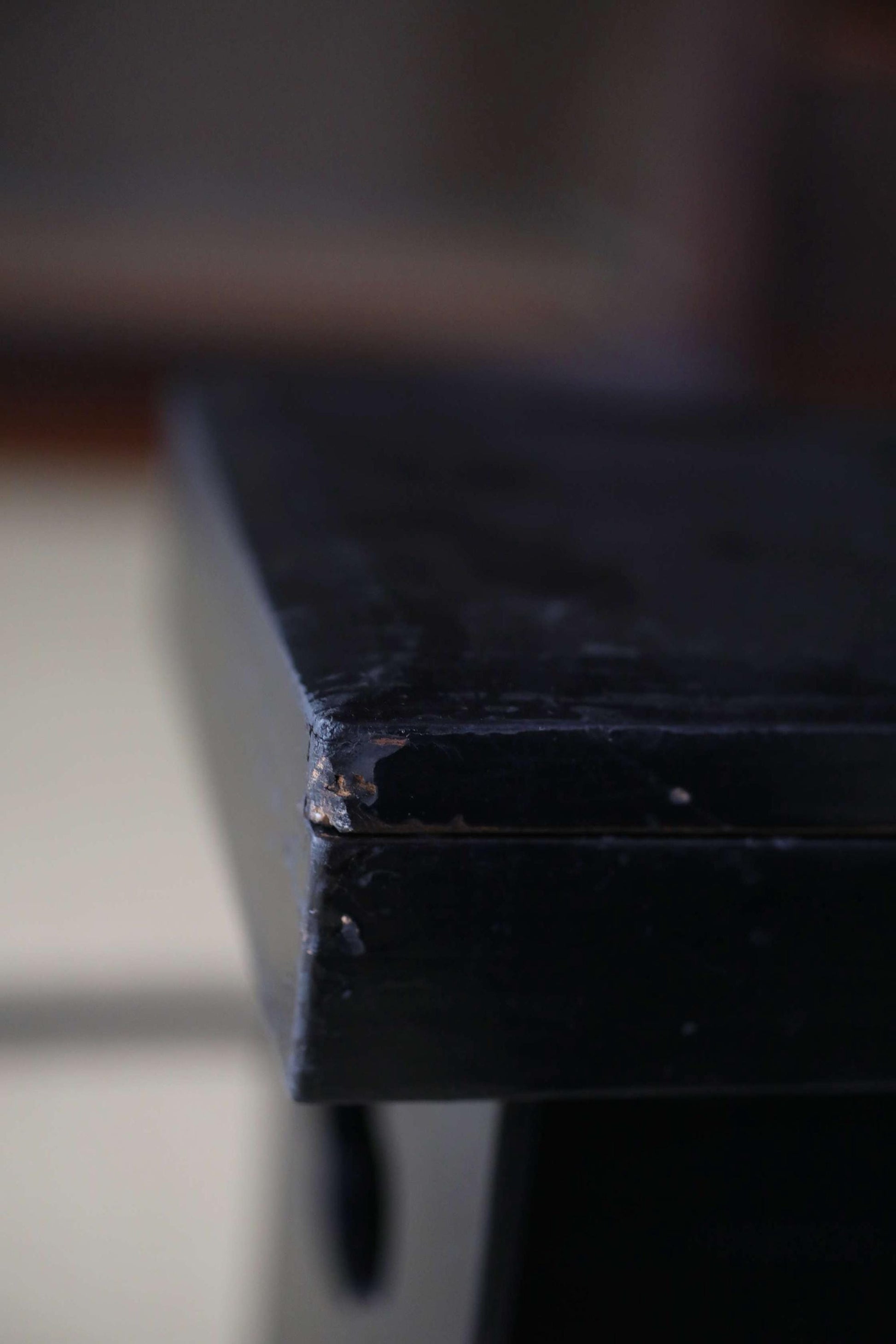A close-up view of a dark wooden surface, possibly a table or cabinet, with a slightly worn and aged appearance.