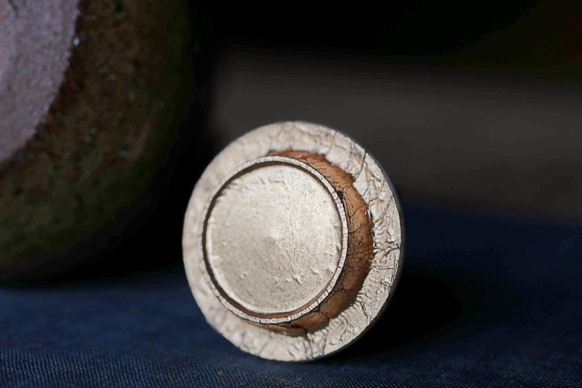 a close-up view of a circular object with a textured surface, possibly a piece of metal or a ceramic item, placed on a dark surface.