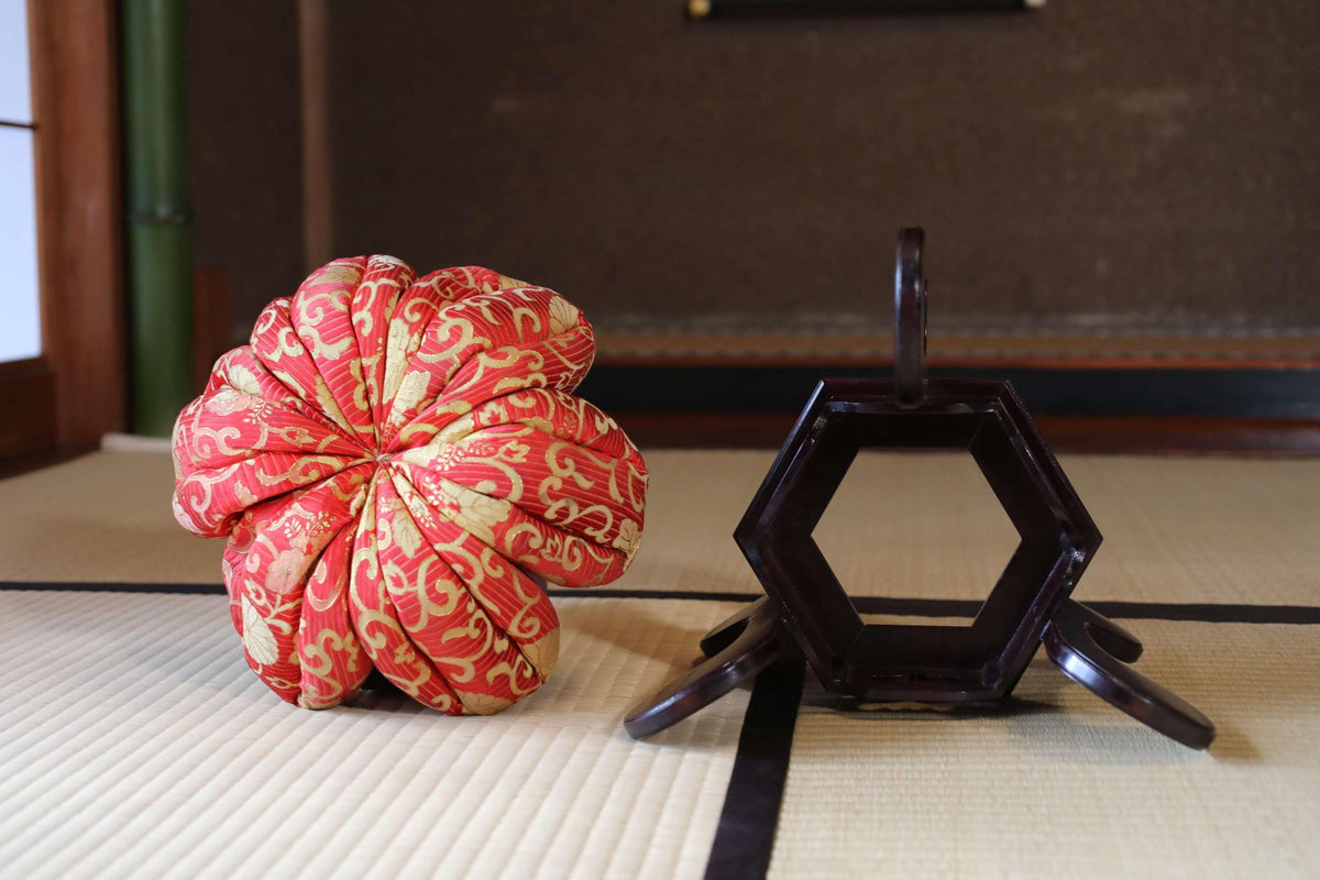 a red and gold flower-shaped object and a black hexagonal object on a white mat.