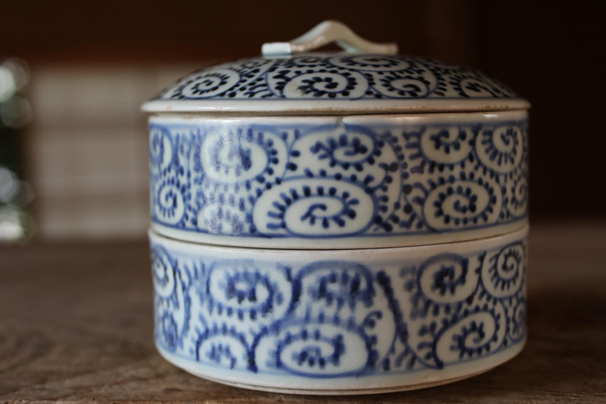 A decorative blue and white ceramic container with a lid, sitting on a wooden surface.
