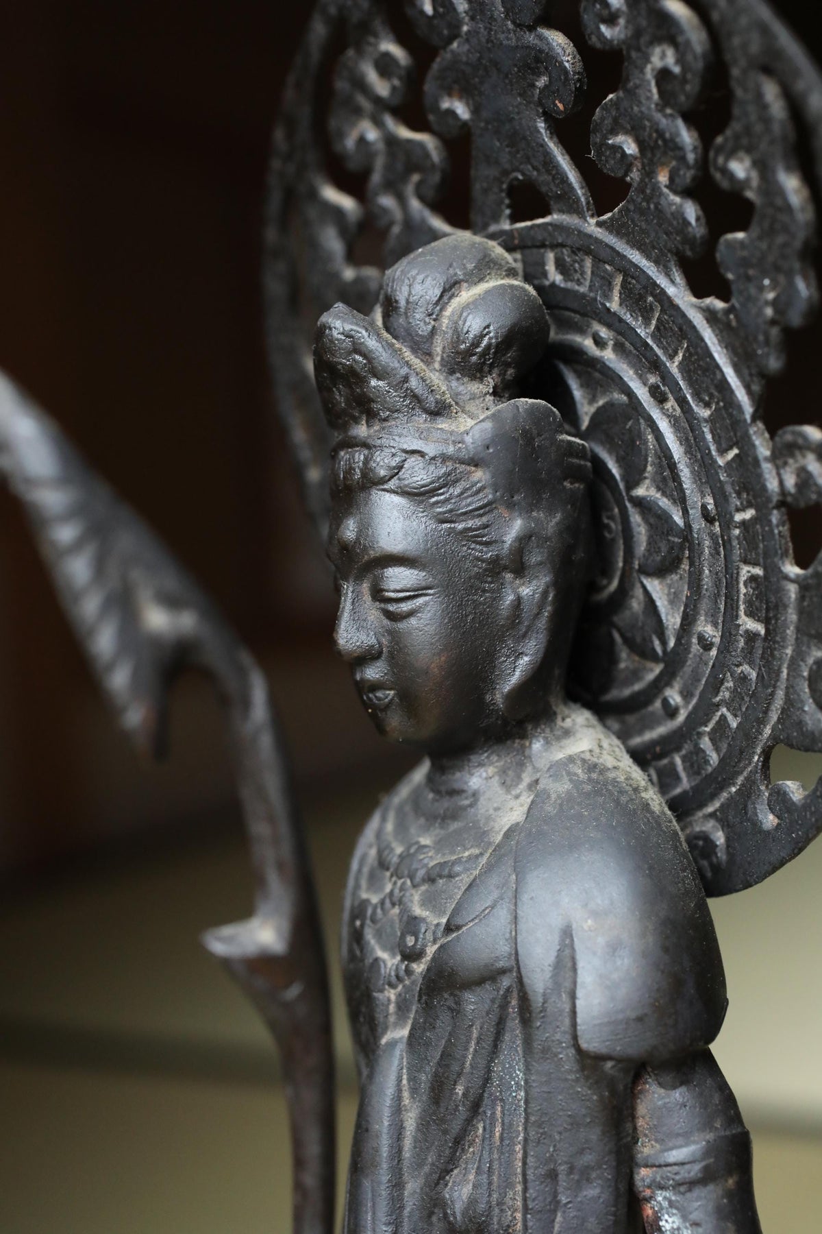 A close-up view of a black metal statue depicting a figure with an ornate headdress.