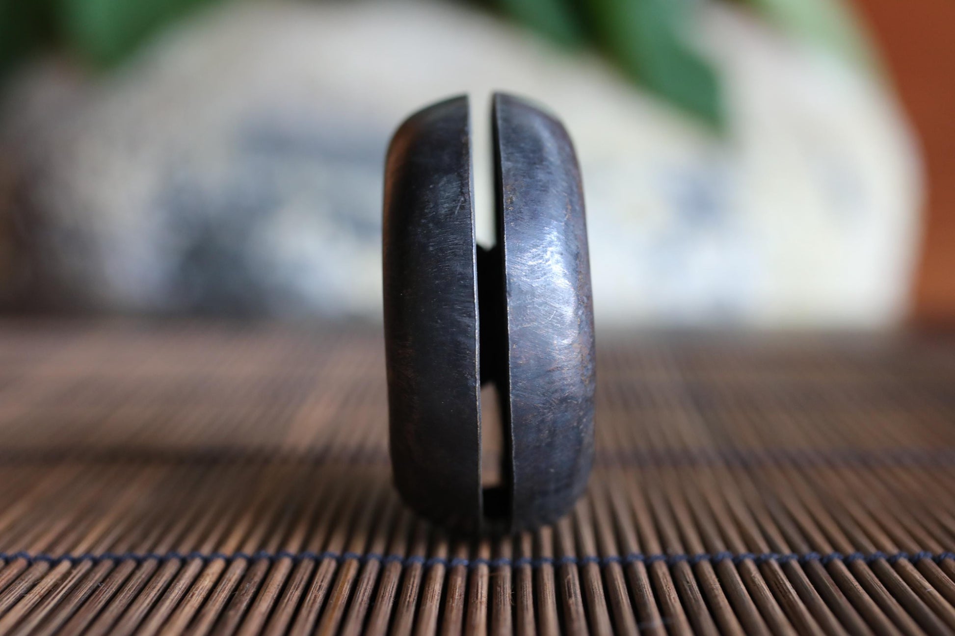 A close-up view of a black metal object, possibly a tool or utensil, placed on a bamboo mat or placemat.