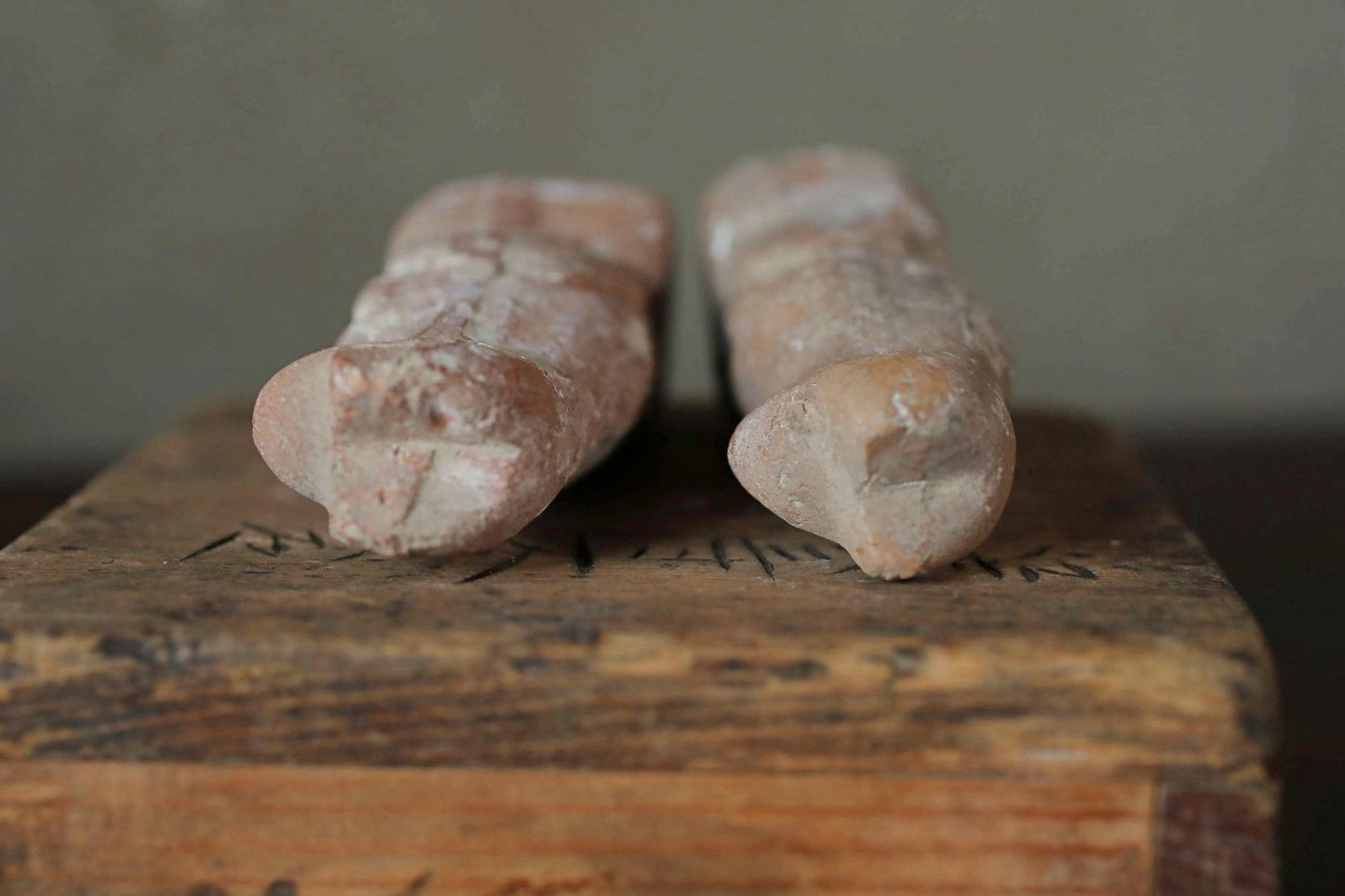 Two ancient artifacts, possibly pottery or sculptures, are displayed on a wooden surface.