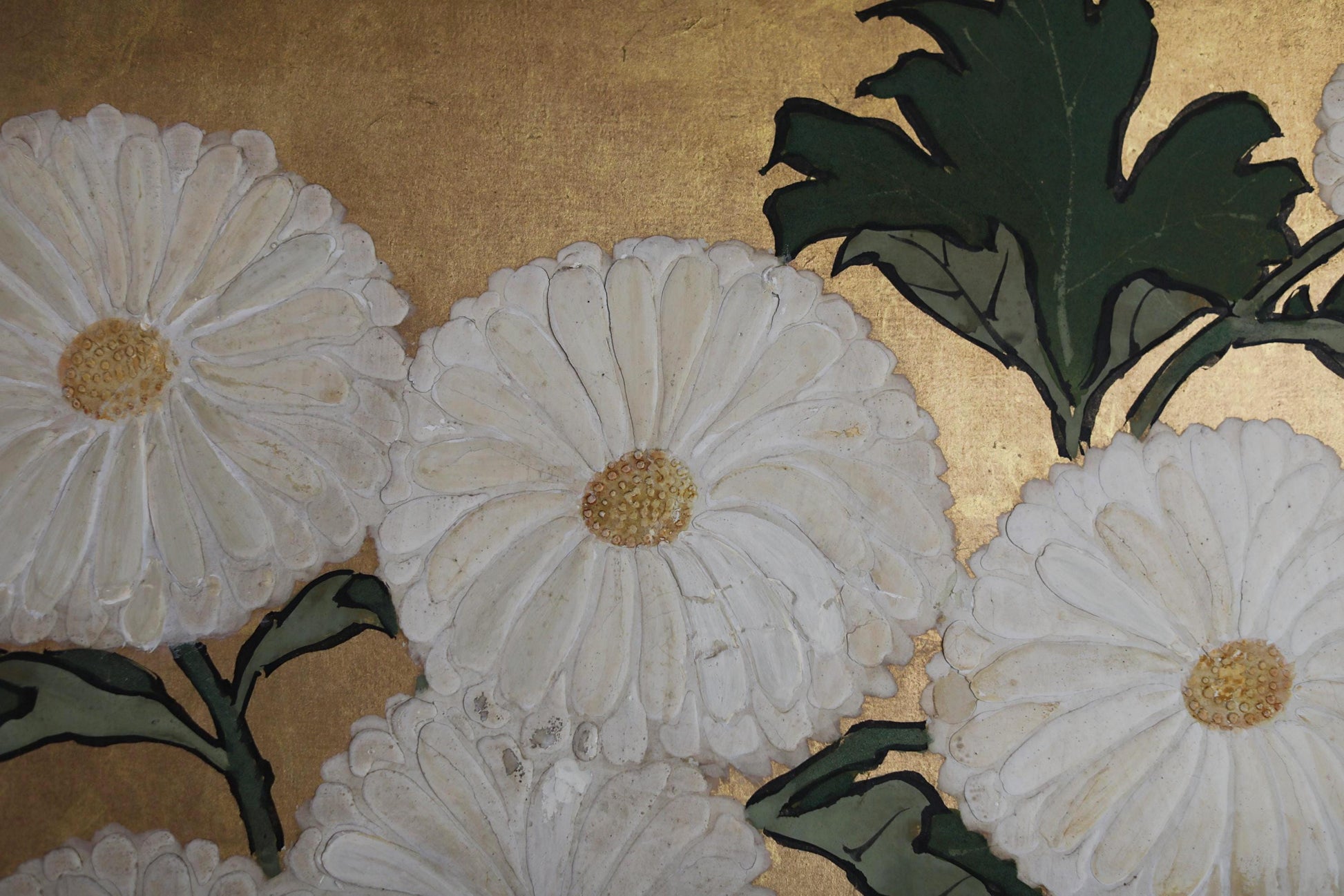 a close-up view of white daisy flowers with green leaves, set against a golden background.