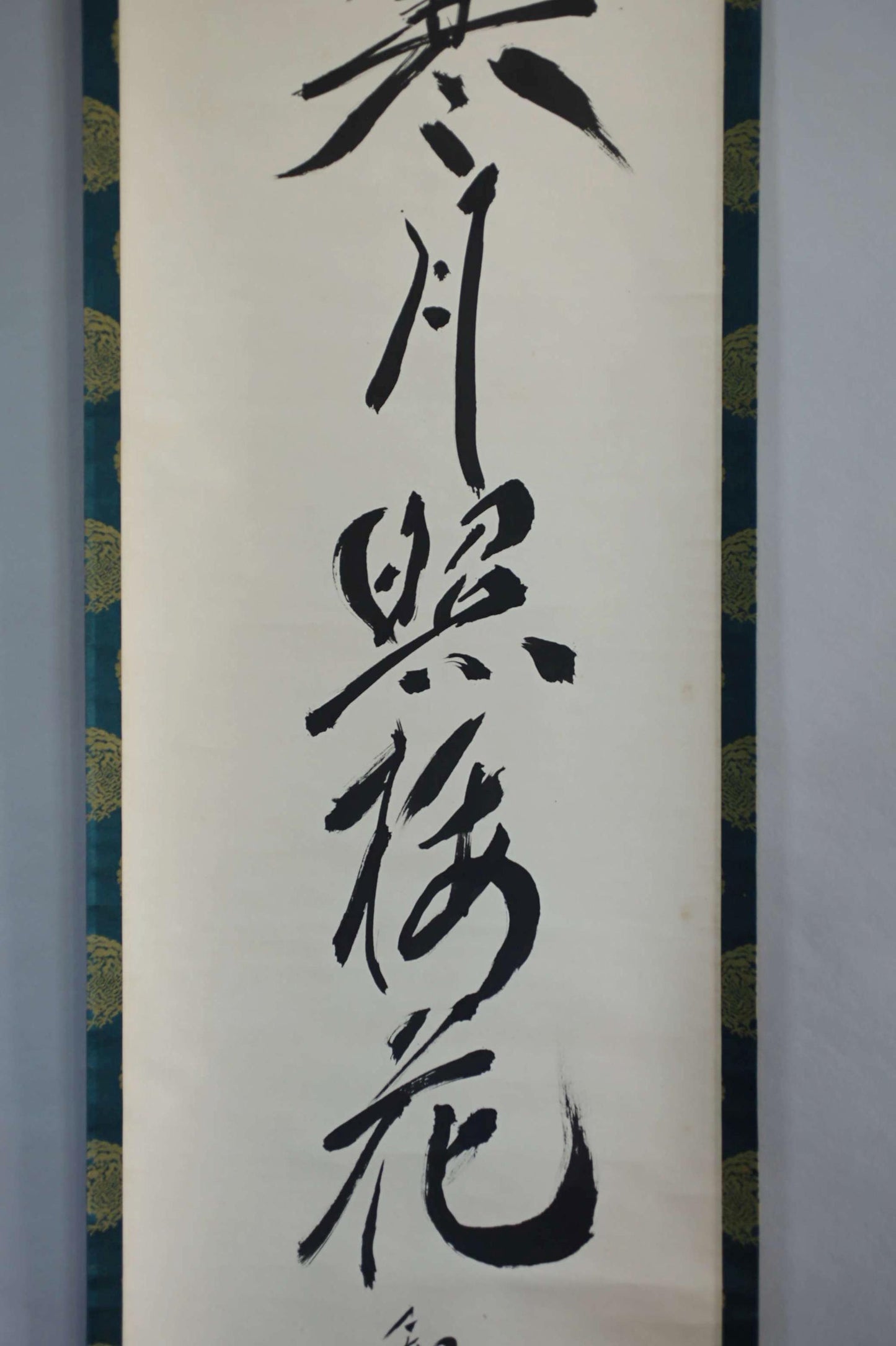 a close-up view of a black and white Chinese calligraphy scroll. The scroll contains several characters in black ink, which are written vertically and appear to be in a traditional Chinese style. The image does not contain any additional text or details that would allow for a detailed description of the content.