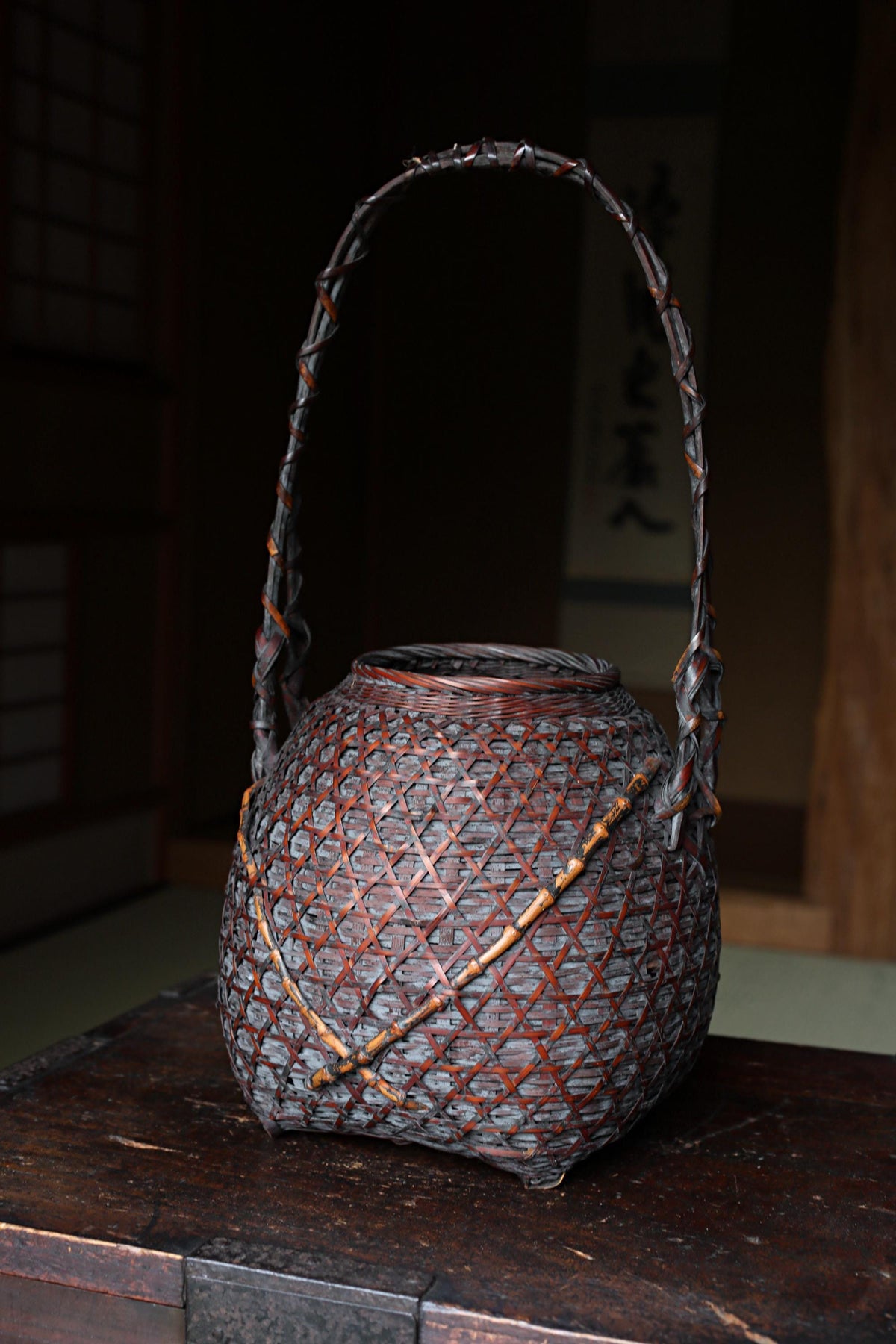 A traditional Japanese woven basket with a curved handle, sitting on a wooden surface.