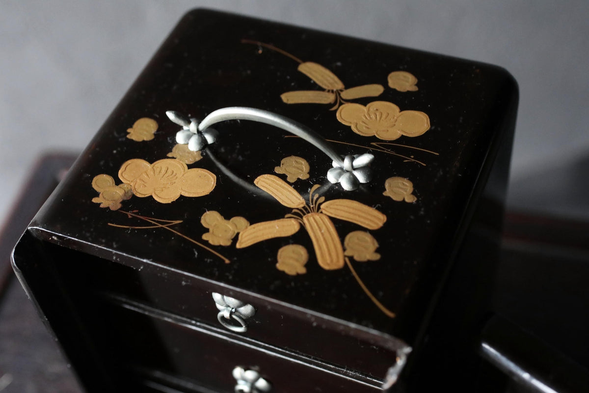 A black wooden box with a decorative floral design on the lid.