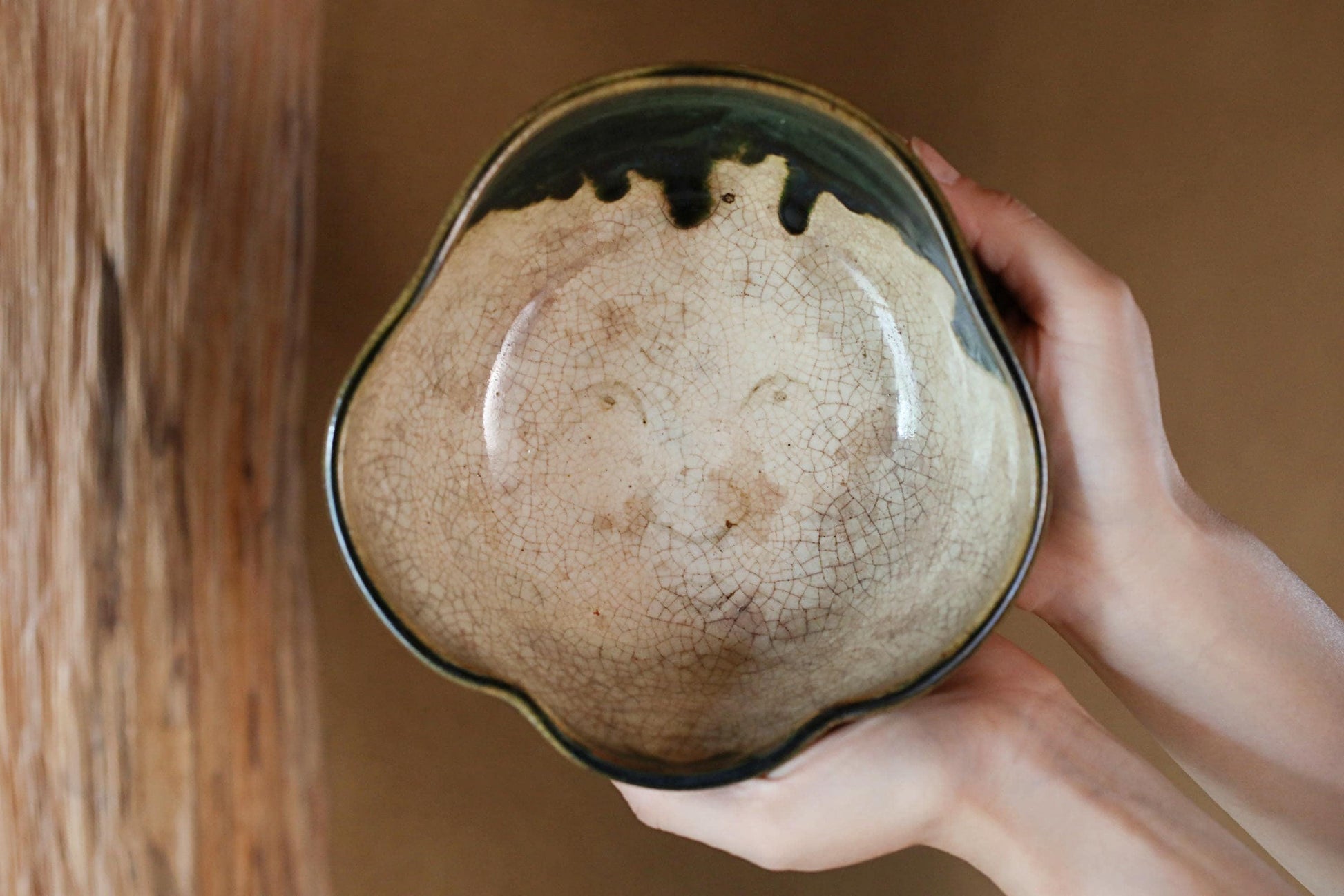 A person's hands holding a ceramic bowl with a face design on it.