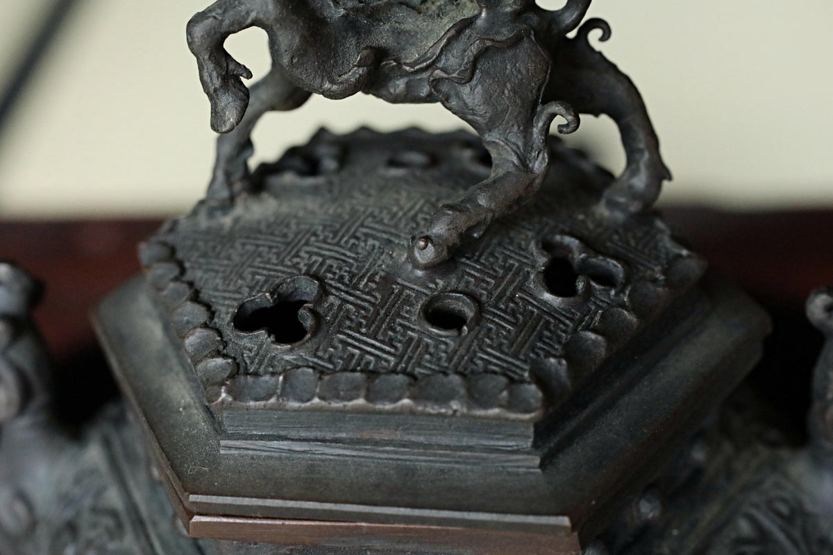 A close-up image of a dark metal sculpture depicting a stylized animal or mythical creature, with intricate details and patterns.