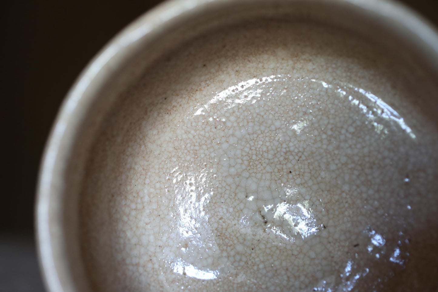 A close-up view of a white ceramic bowl or cup, with a textured surface and a small amount of liquid or substance visible inside.