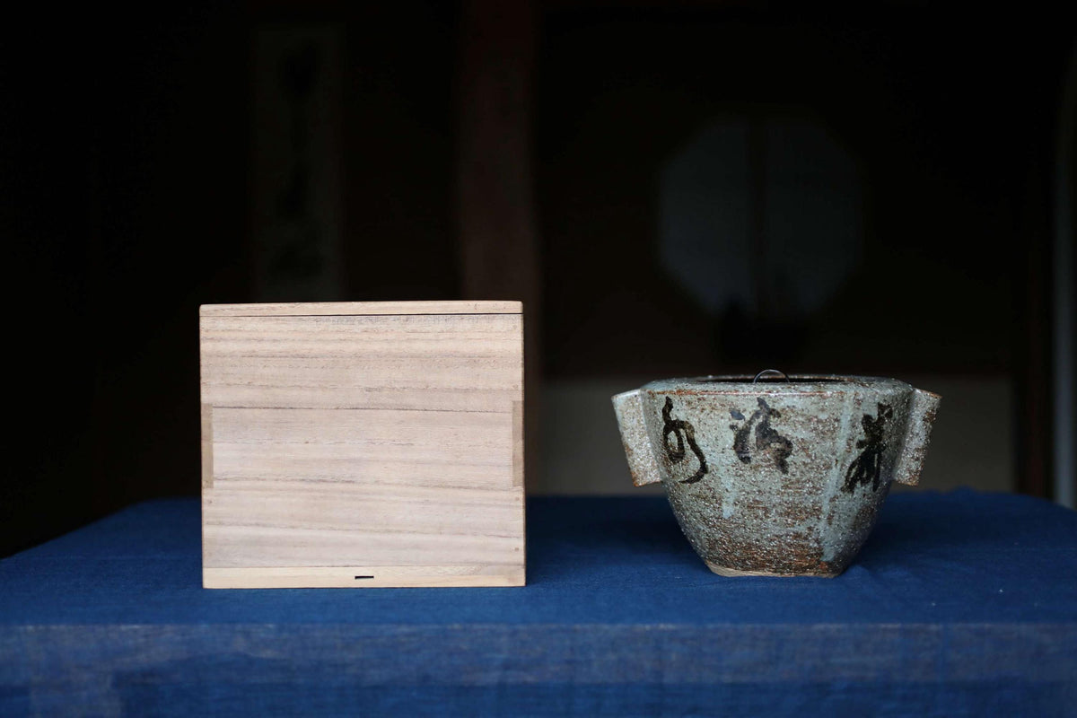 a wooden box and a ceramic teapot placed on a blue surface.