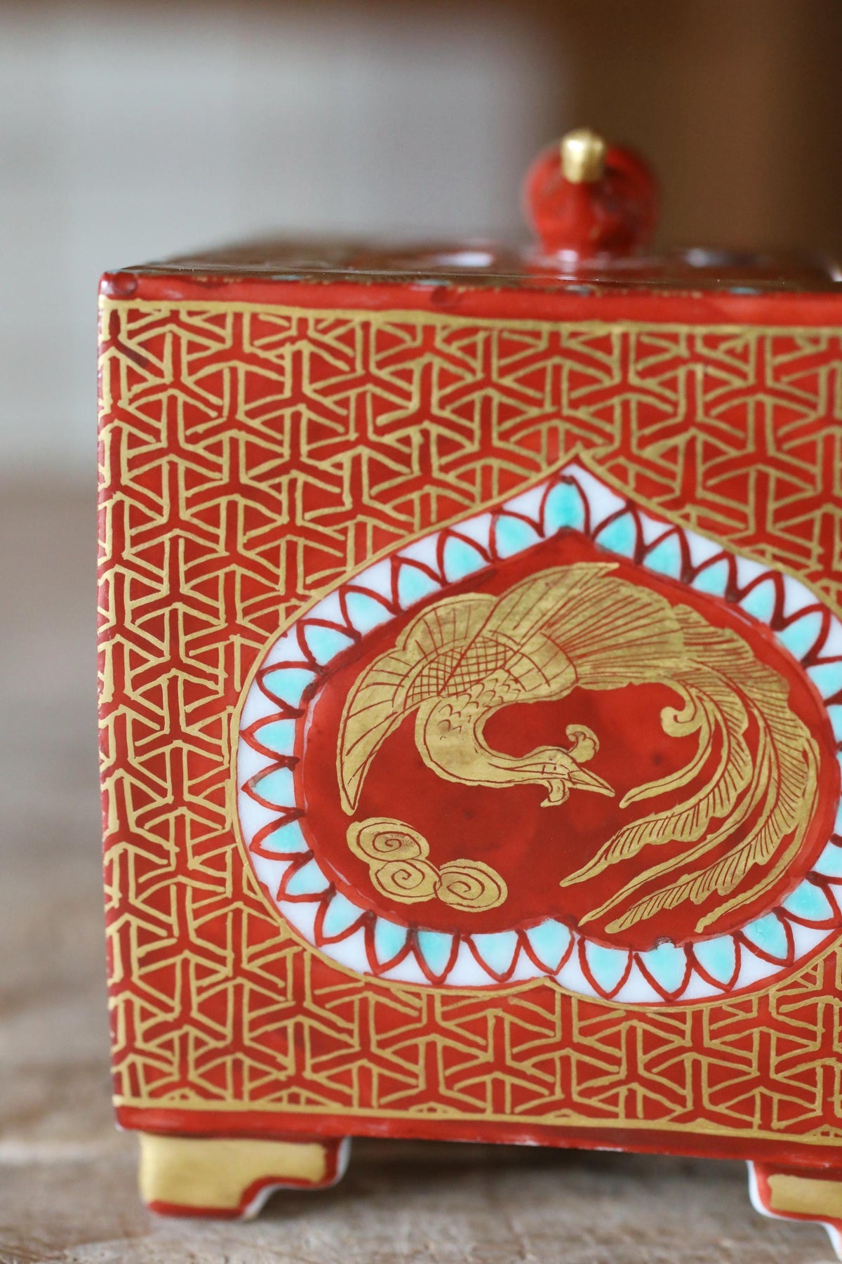 a red and gold decorative box with a gold bird design on the front.