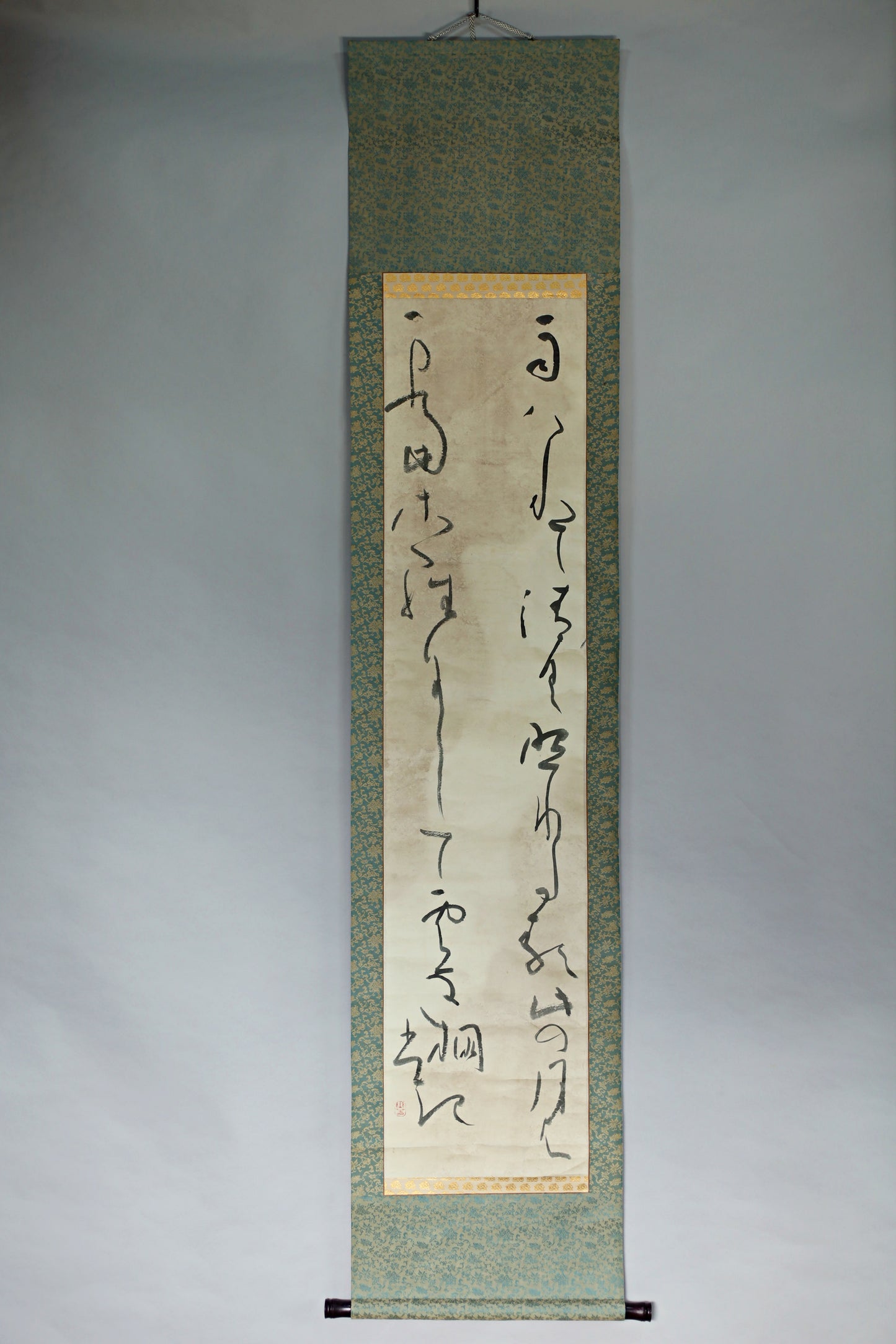 a vertical scroll with Chinese characters on it, hanging on a wall.