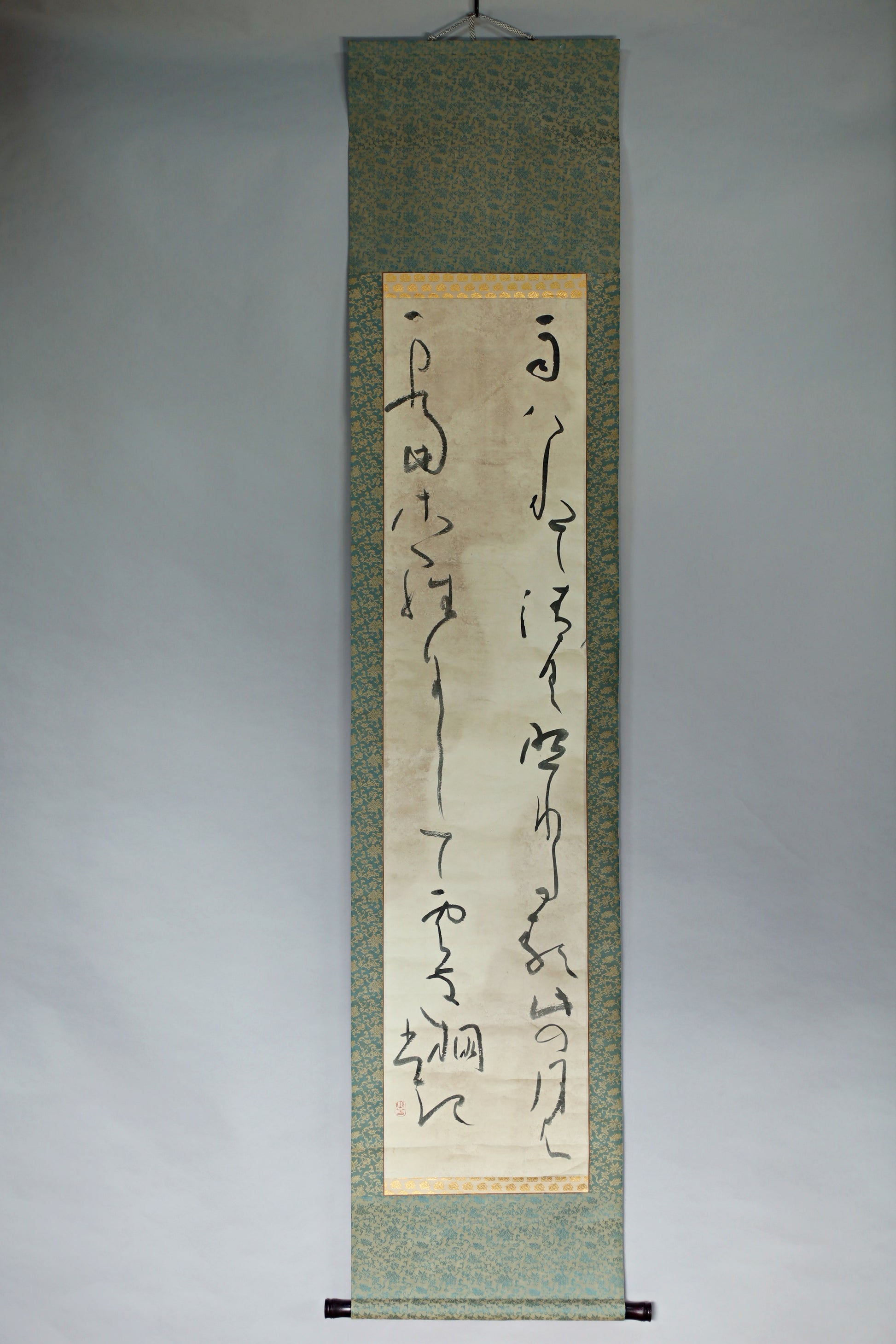a vertical scroll with Chinese characters on it, hanging on a wall.