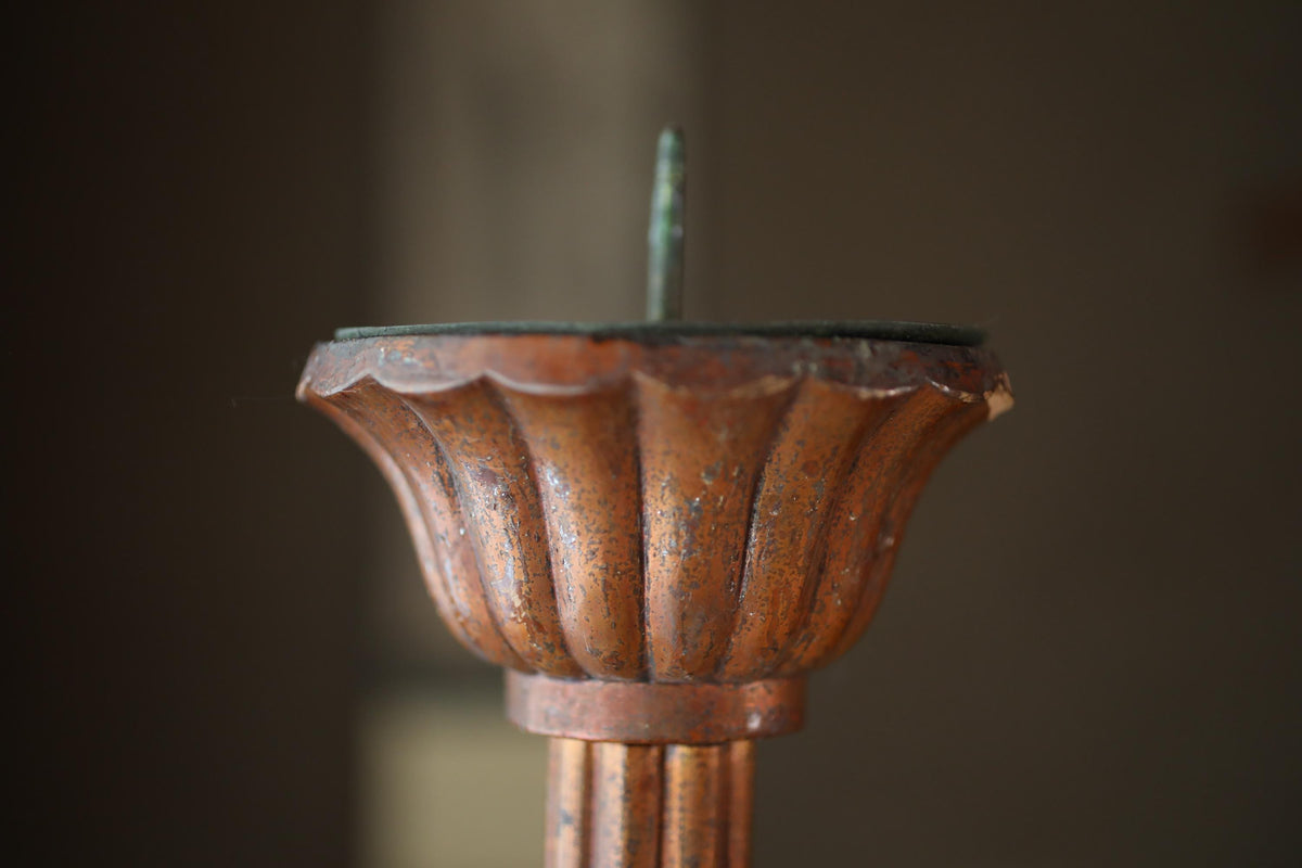 a close-up view of an ornate, antique-looking candle holder with a rusted, weathered appearance.