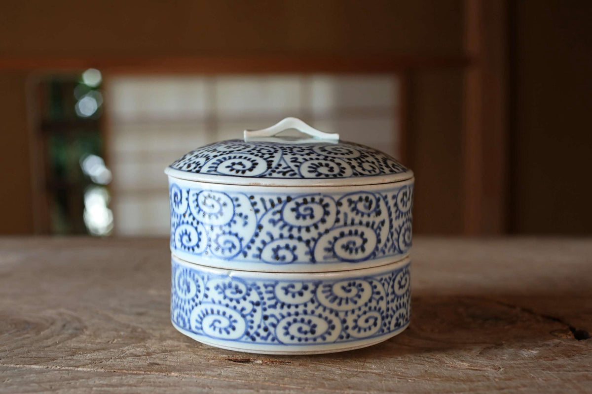 A decorative blue and white ceramic container with a lid sits on a wooden surface.