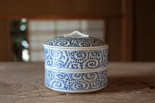A decorative blue and white ceramic container with a lid sits on a wooden surface.