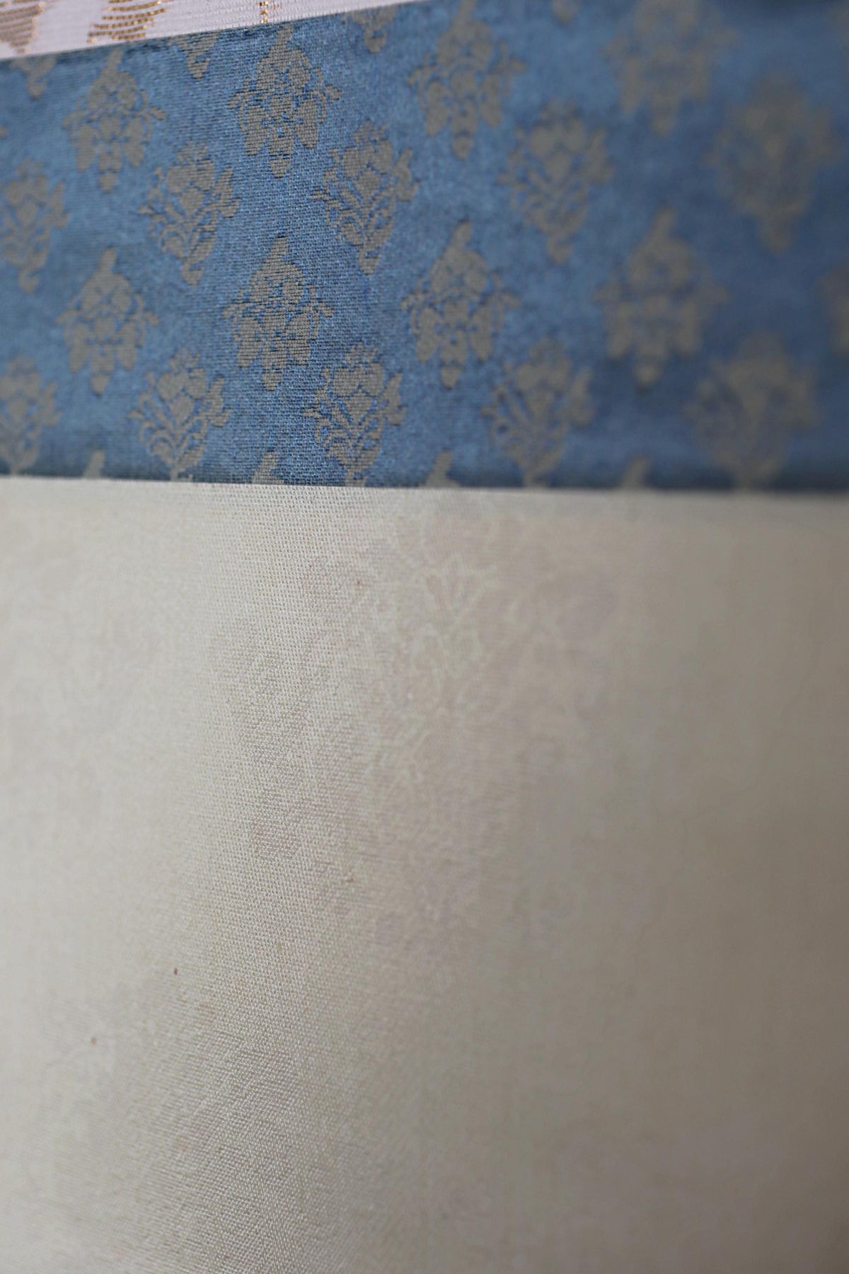 The image is a close-up of a fabric with a blue floral pattern, overlaid on a plain white fabric.