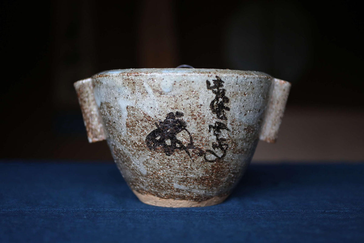 A ceramic bowl with a black design on it, sitting on a blue surface.