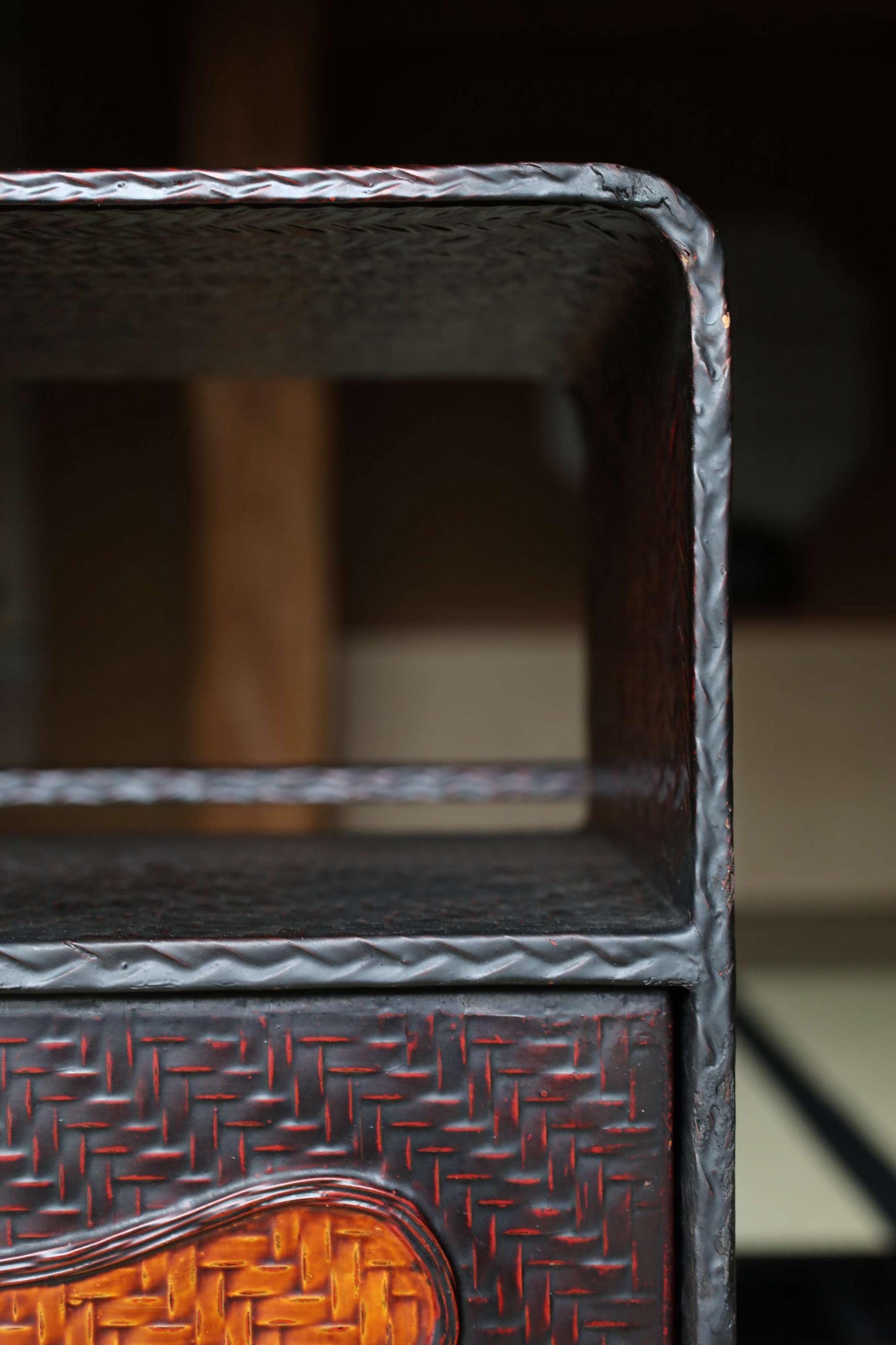a close-up view of a dark metal structure with a woven pattern, possibly a piece of furniture or a decorative element.