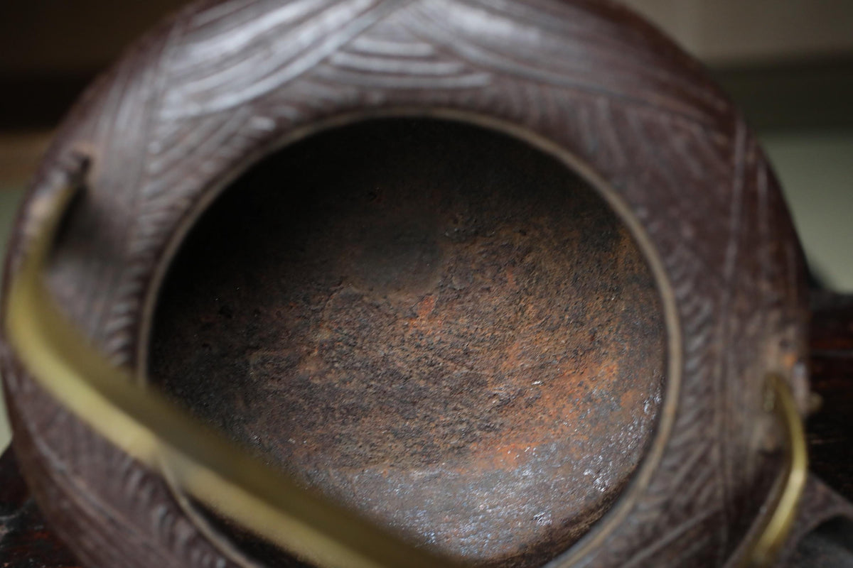 A close-up view of a rusted metal object, possibly a piece of pottery or a container, with a textured surface and a hole in the center.