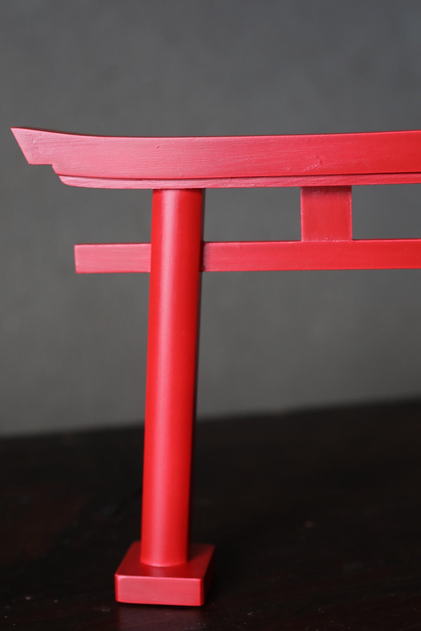 A close-up view of a red torii gate, a traditional Japanese Buddhist gate, against a dark background.