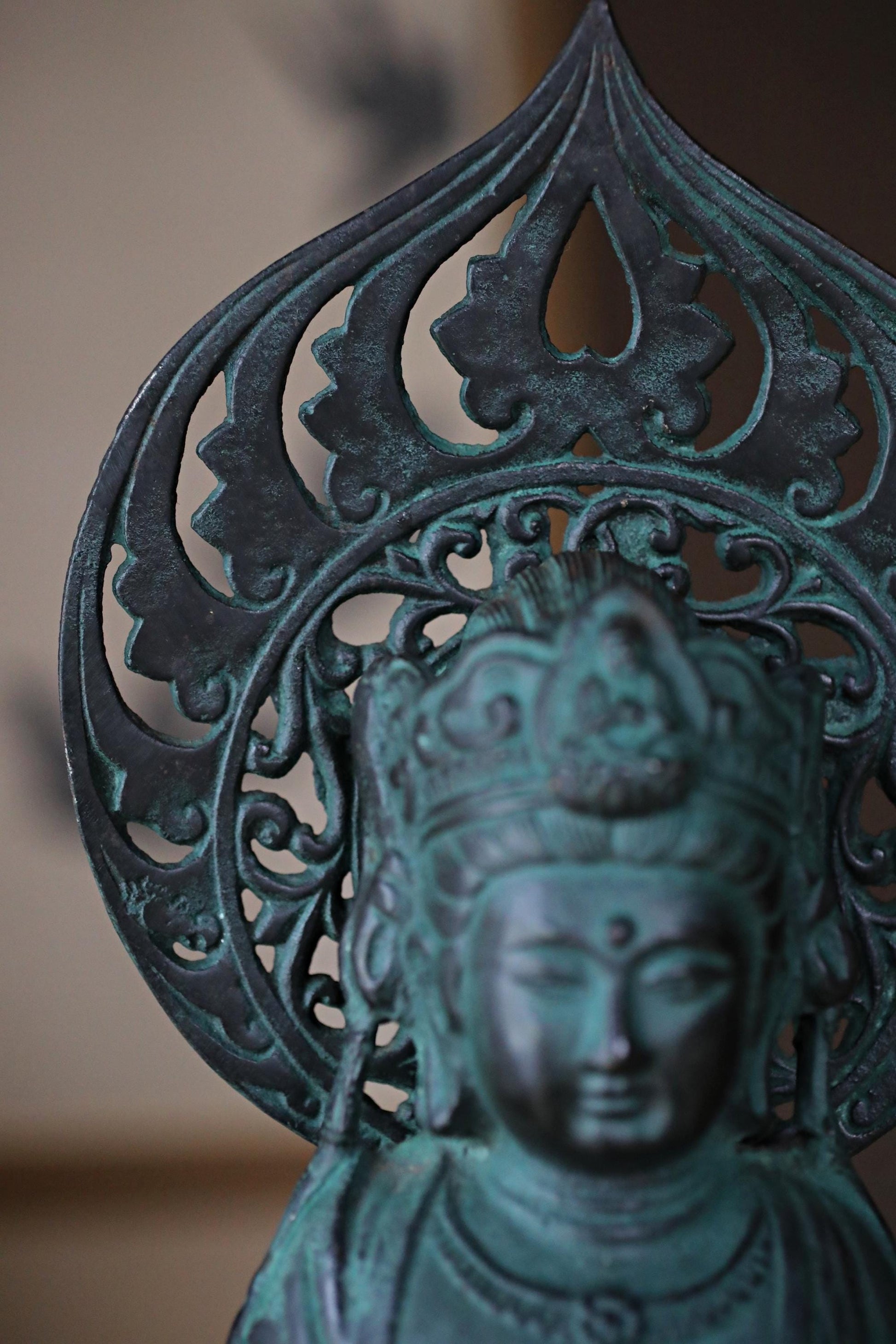 A close-up view of a bronze statue of a deity, with intricate designs and patterns on the headdress.