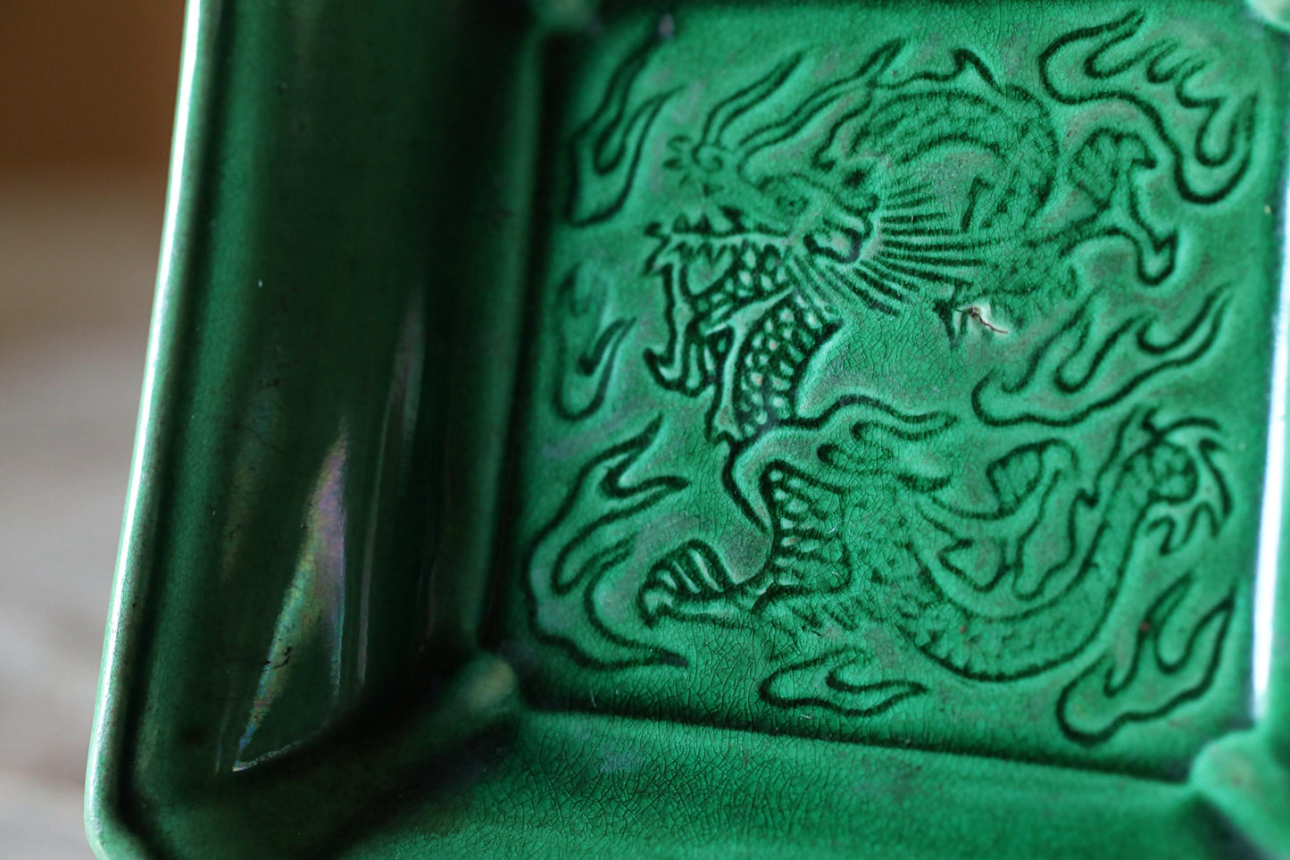 A close-up image of a green ceramic dish with an intricate dragon design on it.