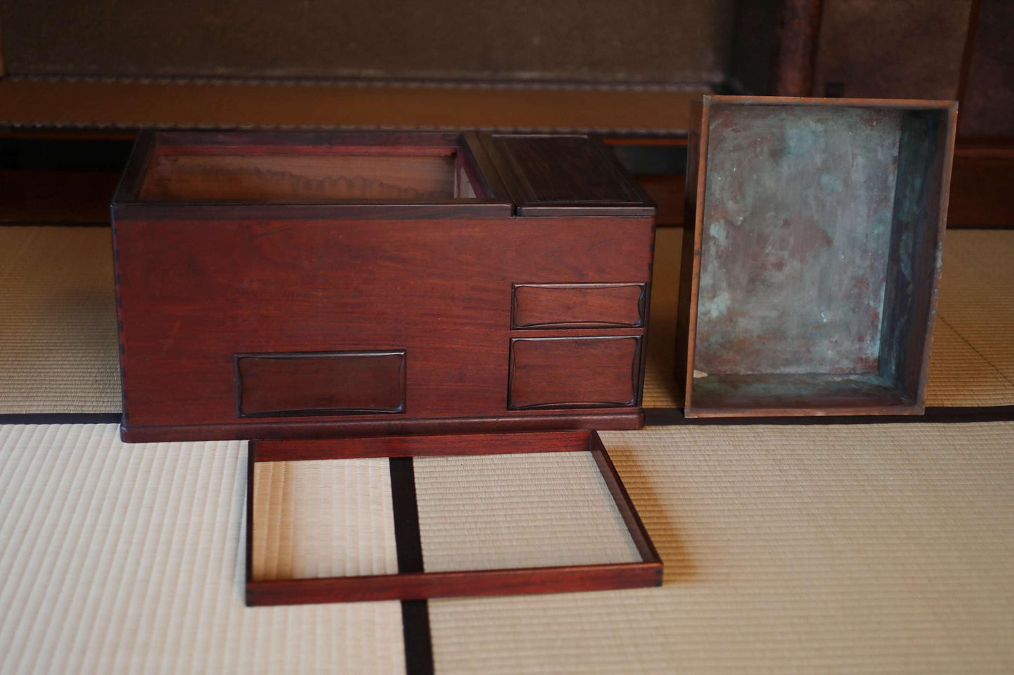 a wooden box with a metal lid, placed on a tatami mat.