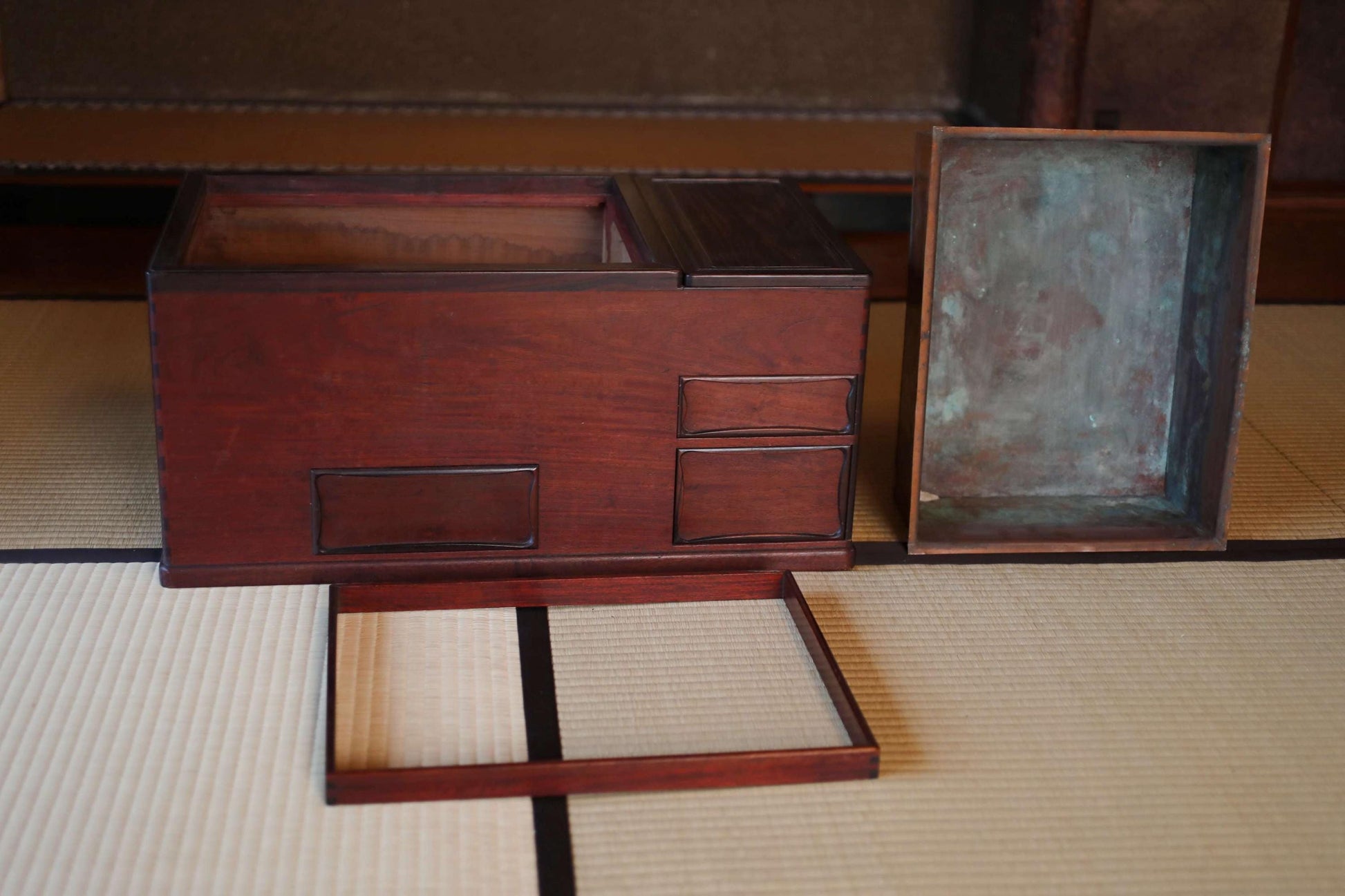 a wooden box with a metal lid, placed on a tatami mat.