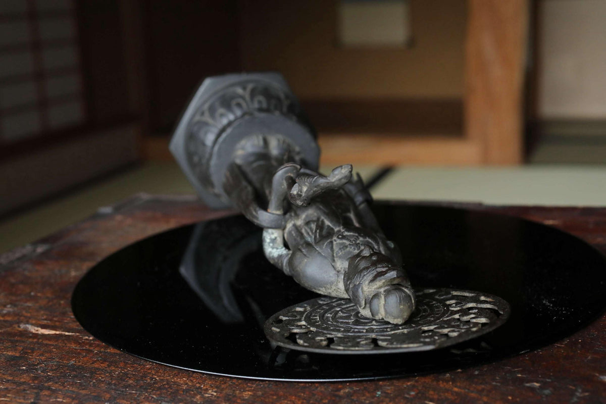 a black metal sculpture of a hand resting on a circular black plate.