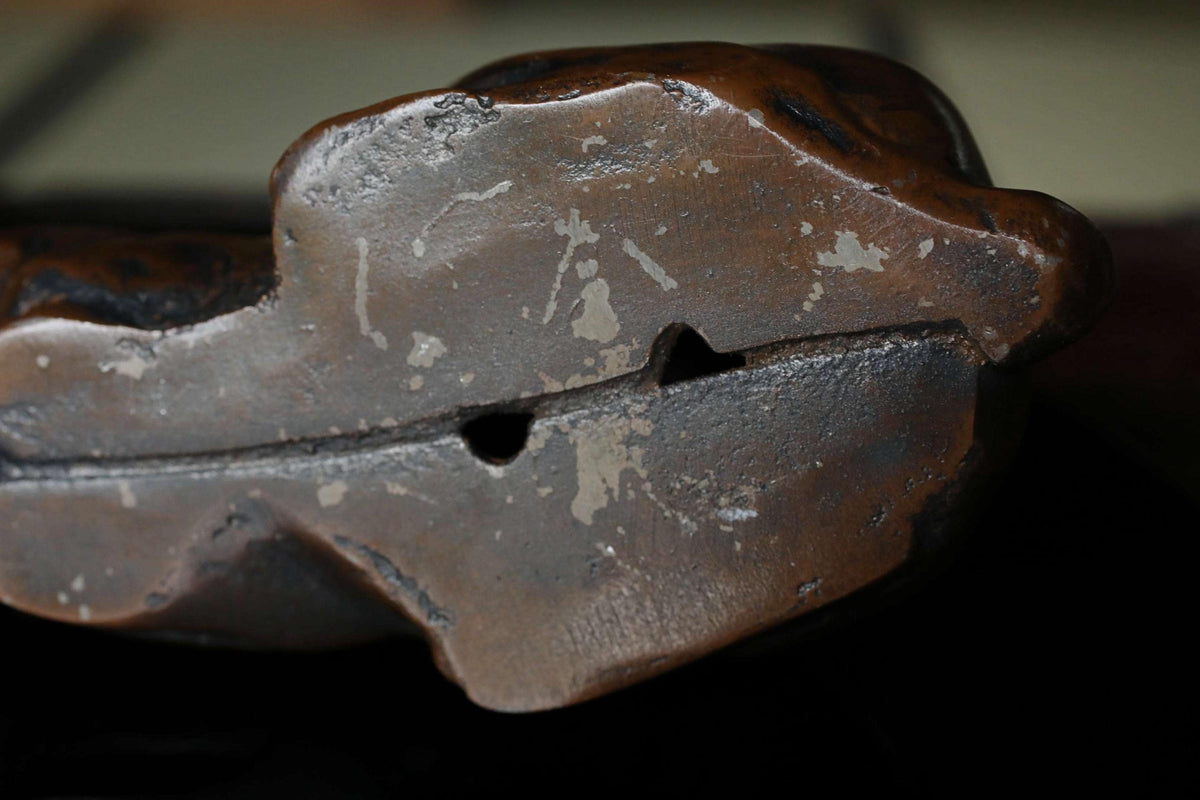 a close-up view of a dark brown, weathered object with a rough, textured surface.