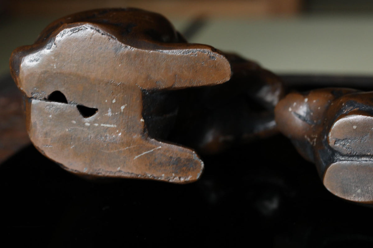 A close-up view of a dark brown, weathered metal sculpture with a textured surface.