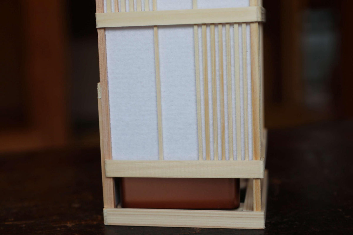 A wooden structure with a white panel and a brown base, possibly a piece of furniture or a decorative item.