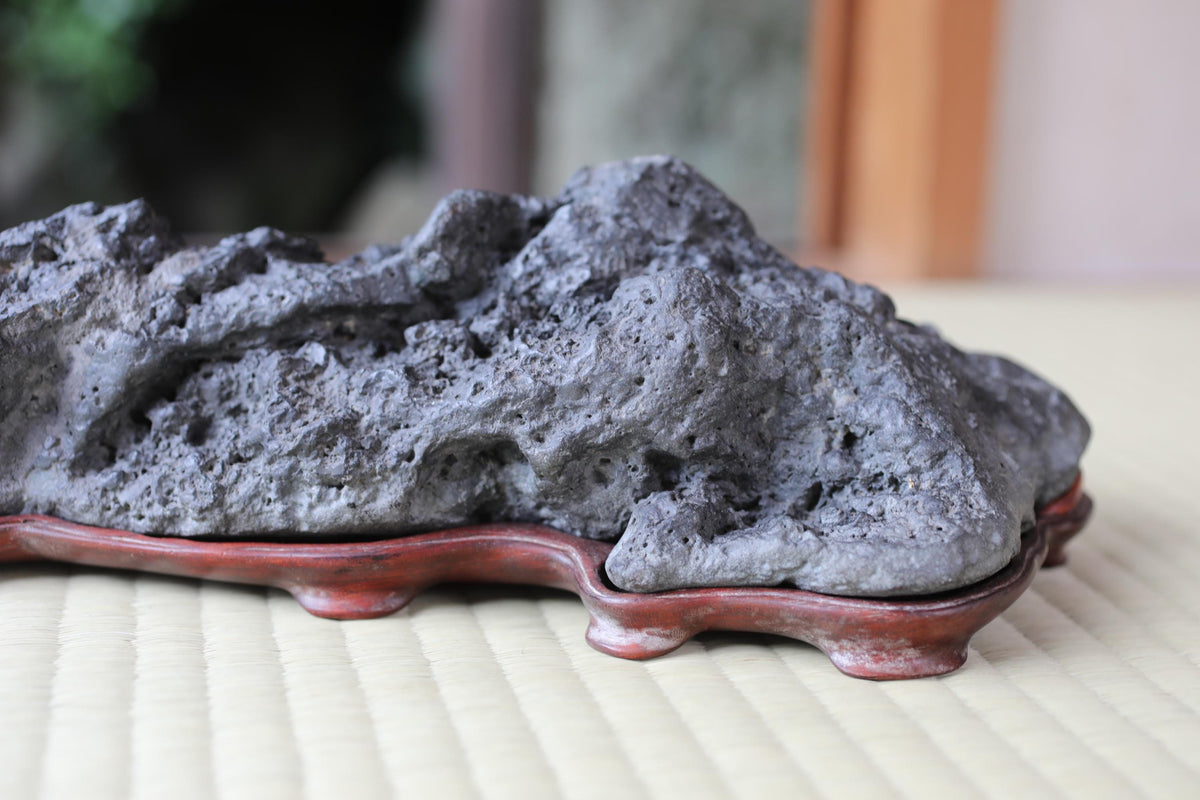 A close-up image of a large, gray rock or stone placed on a red stand or base, with a blurred background.