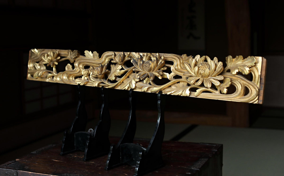 a decorative wooden panel with intricate floral designs, displayed on a wooden stand.