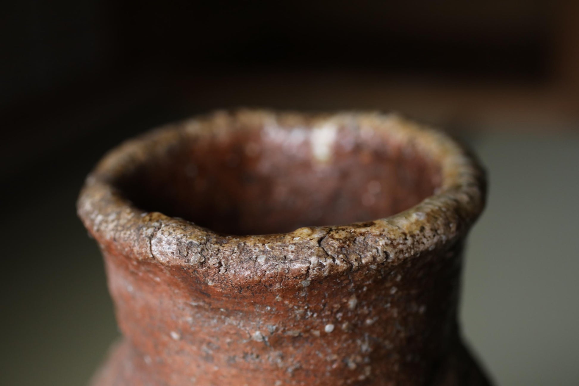 A close-up image of a weathered, brown ceramic vase with a rough, textured surface.