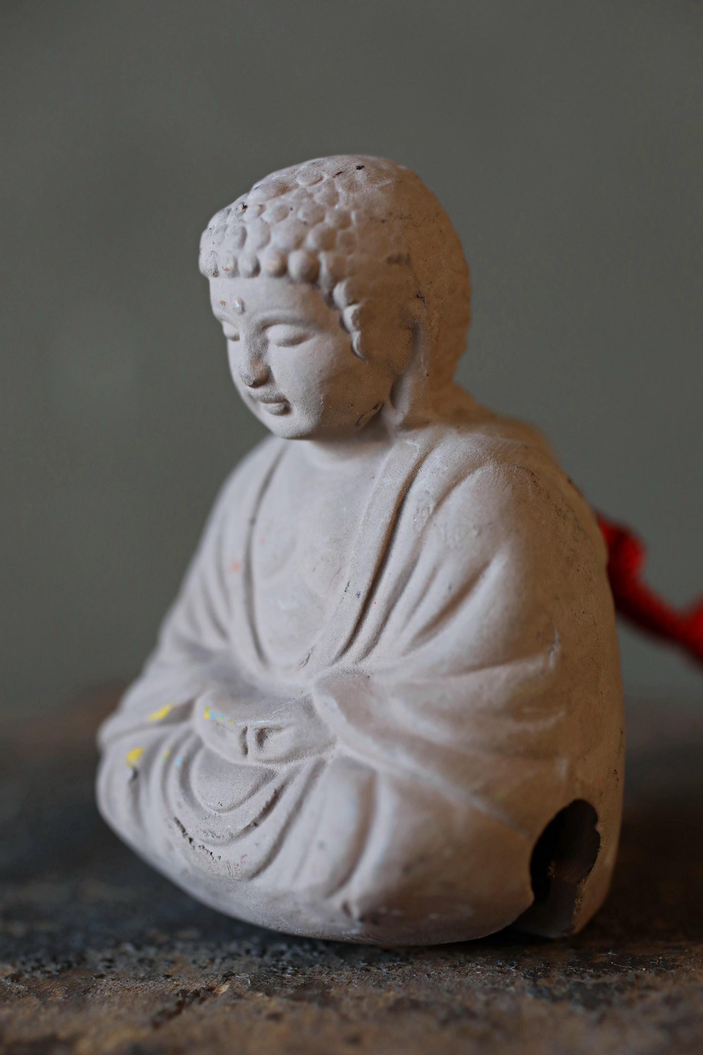 A small white Buddha statue sitting on a gray surface.