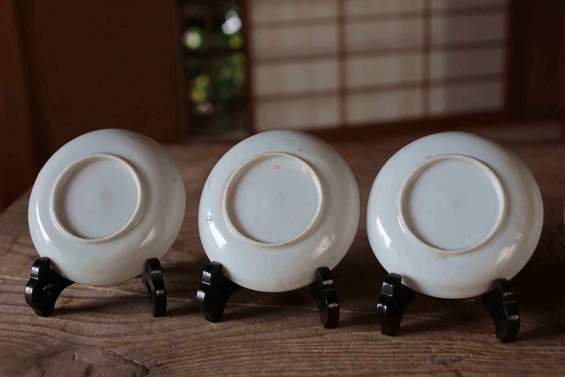 Three white plates with black bases are arranged on a wooden surface, with a blurred background.