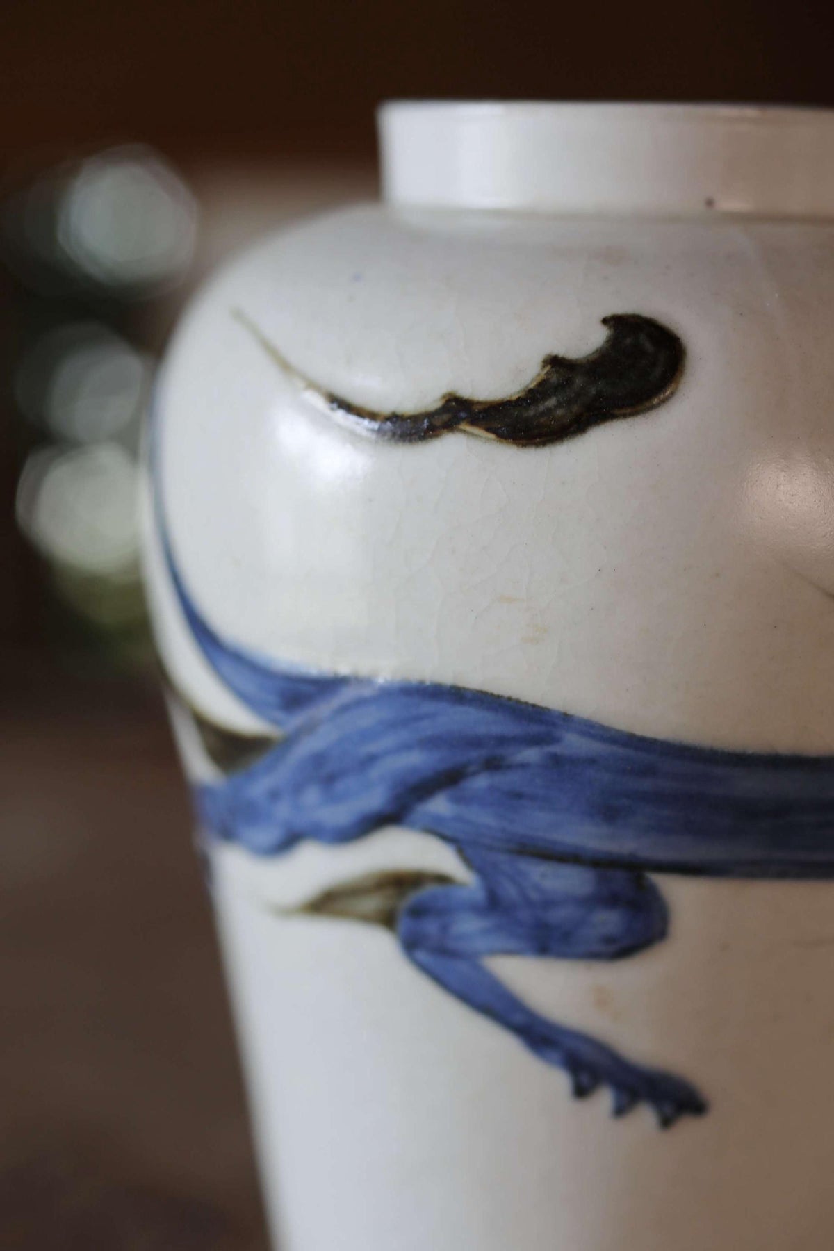 A close-up image of a white vase with a blue and black design depicting a stylized fish or sea creature.