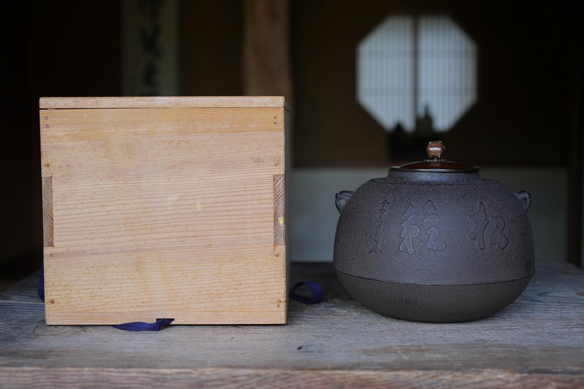 a wooden box and a black teapot on a wooden surface.