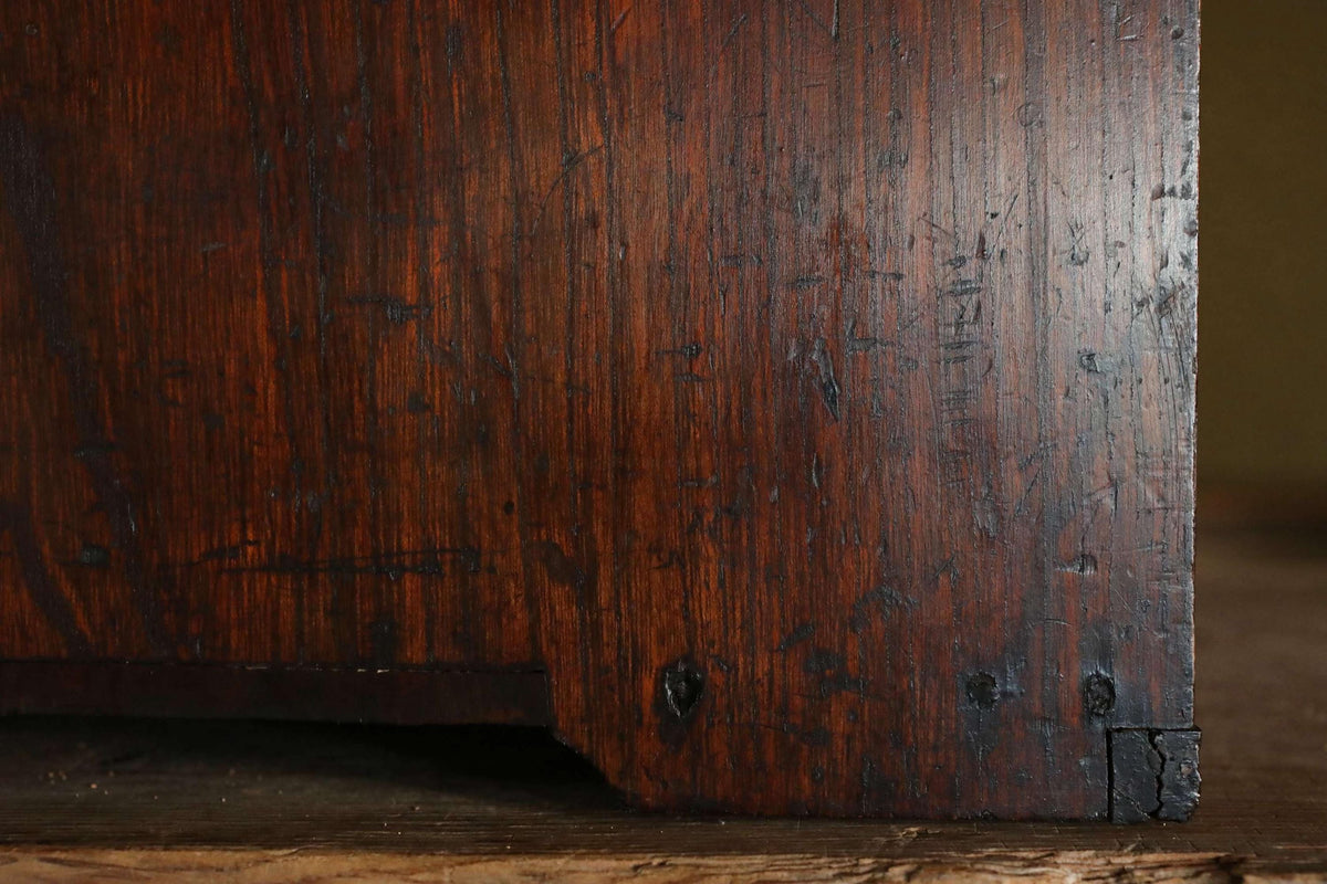 a close-up view of a dark wooden surface with visible grain and texture, giving it a rustic and aged appearance.