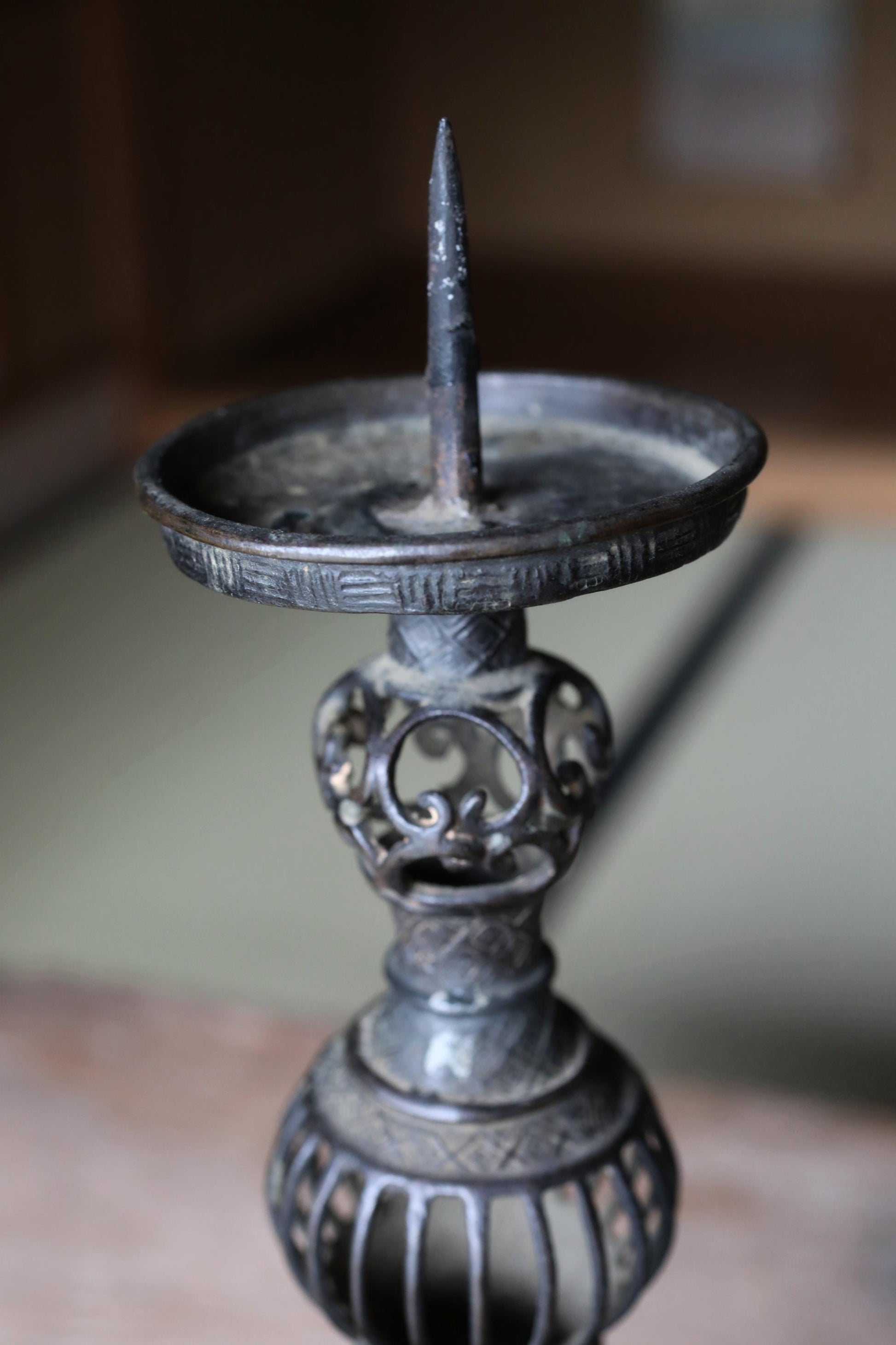 An antique candlestick with a decorative metal design and a pointed top.